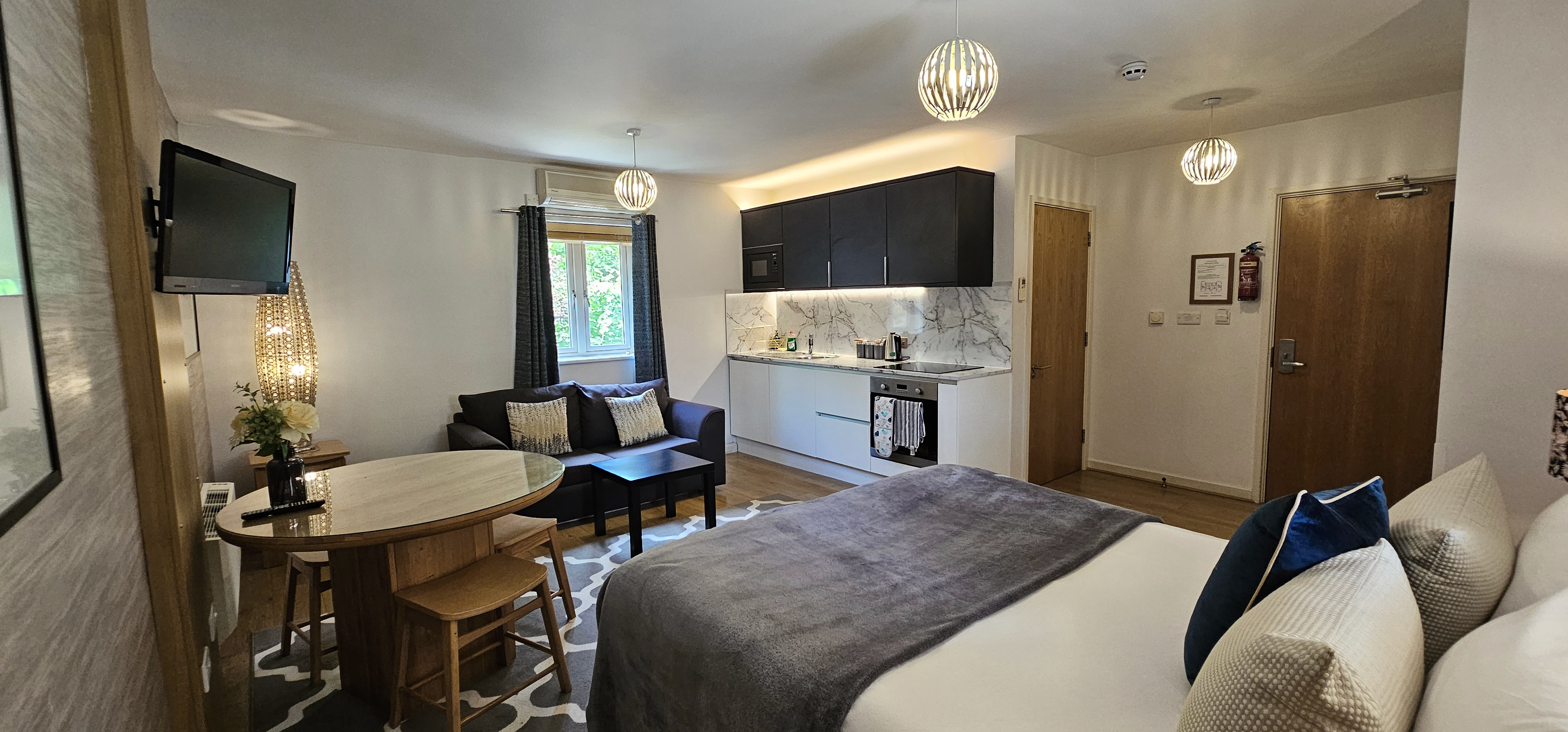 Studio Suite with king size bed, dining table, sofa, kitchenette & door to ensuite bathroom