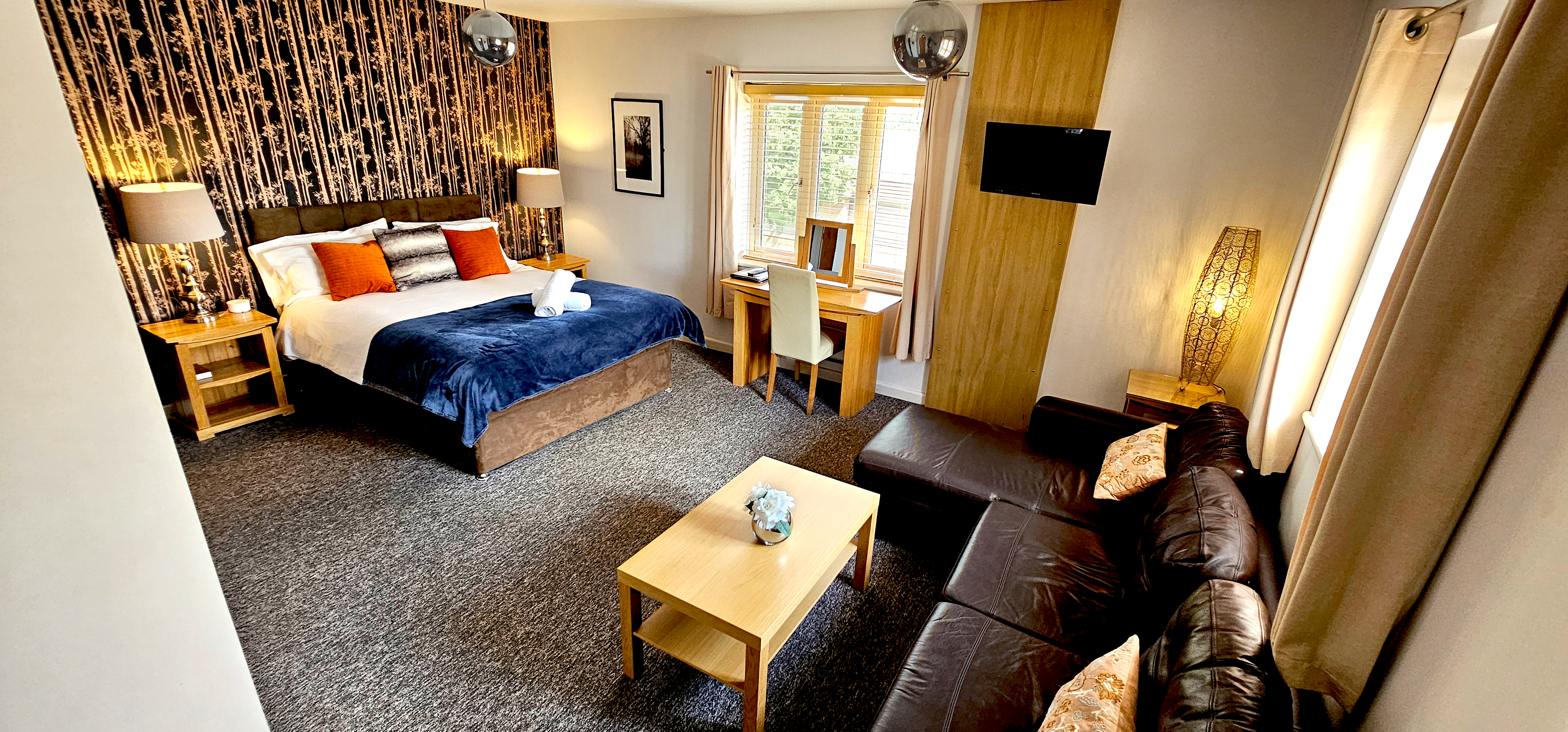 Large deluxe room with king size bed, writing desk & leather corner sofa with coffee table