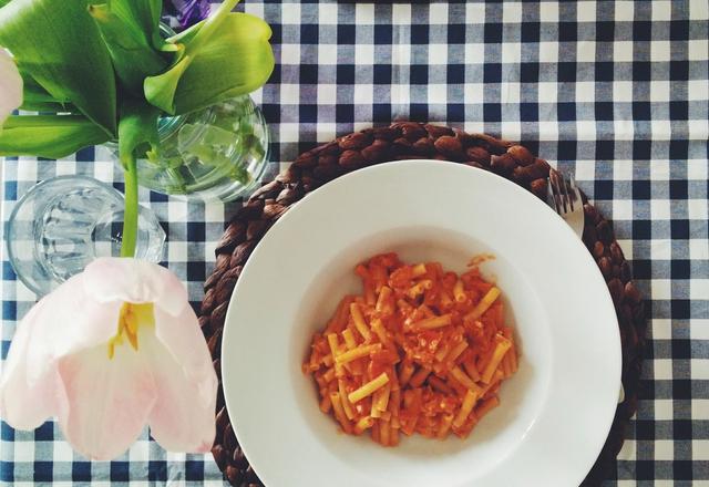 Teller Penne in Tomatensauce auf kariertem Tischtuch