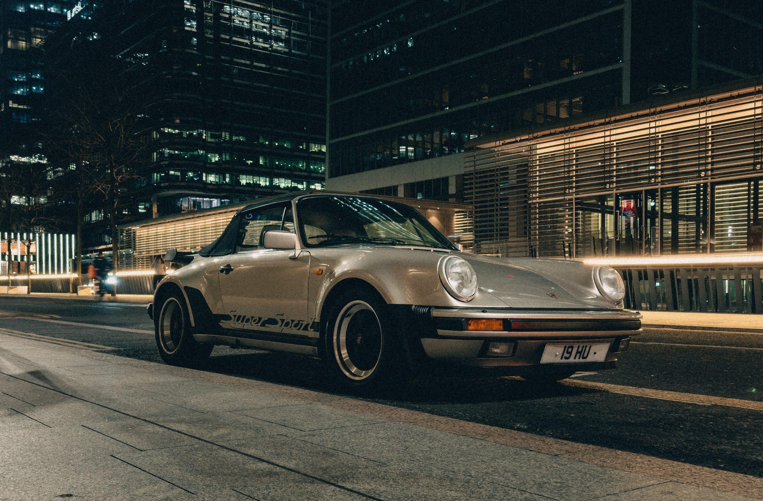 Vintage cream Porsche 911 convertible parked on a city street at night