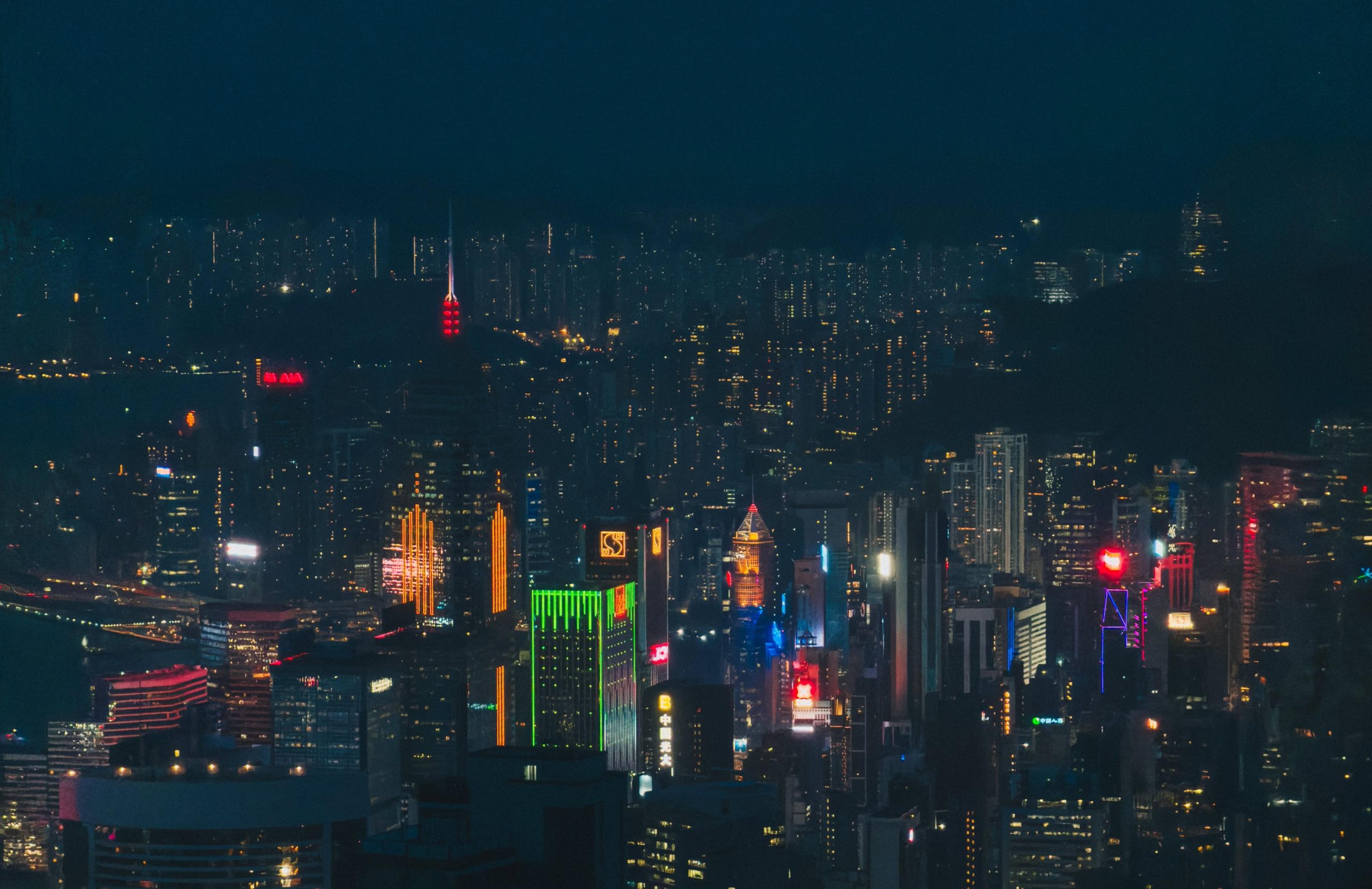 Hong Kong skyline lit up at night with neon signs against a dark hillside