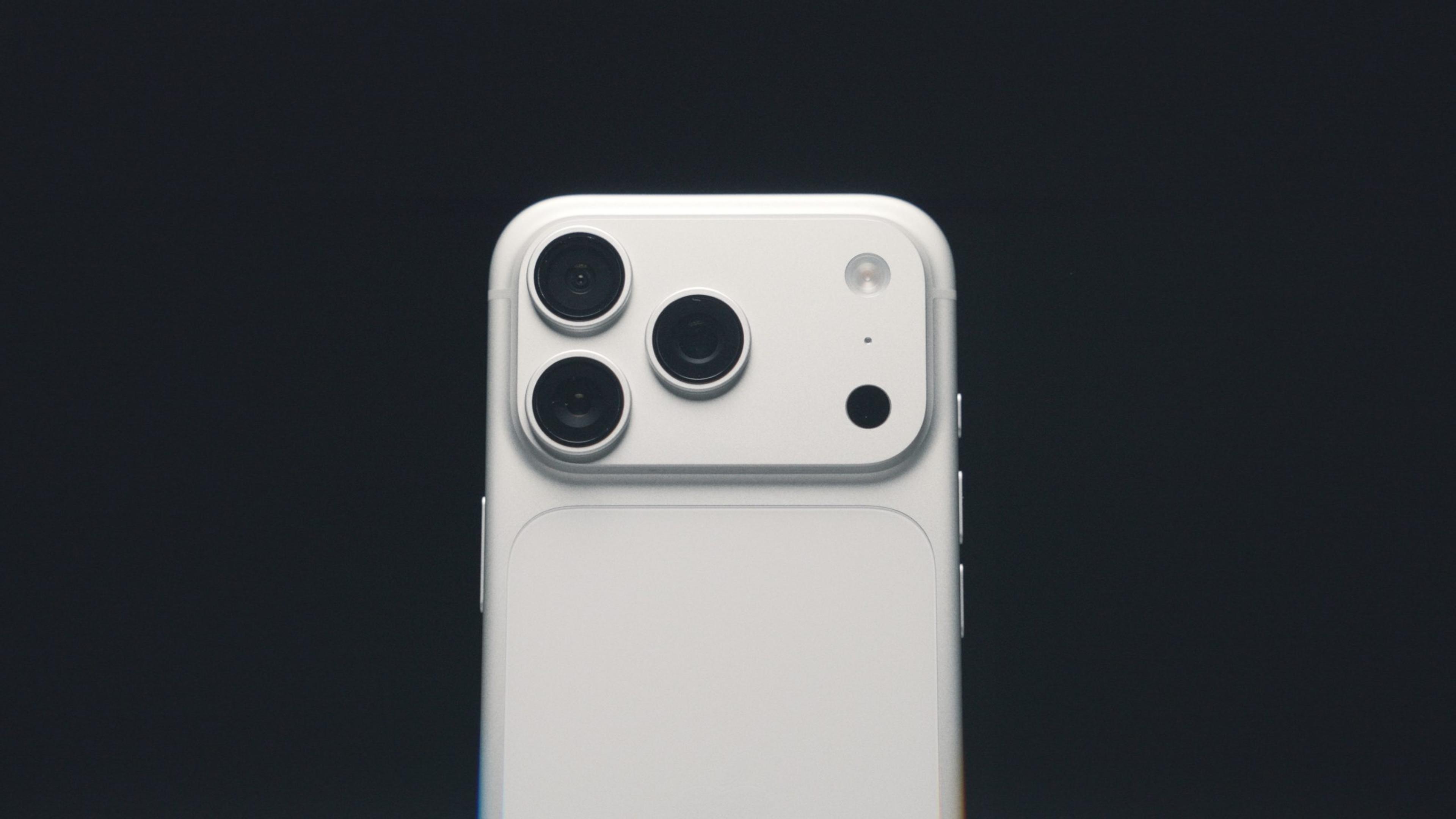 Close-up of an iPhone's triple camera lenses on a white phone against a dark background