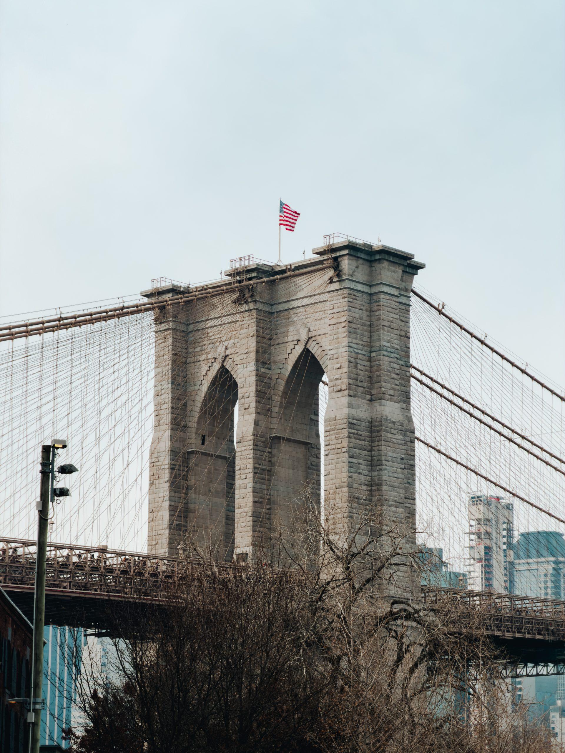 One of the Brooklyn Bridge's stone towers with an American flag flying on top