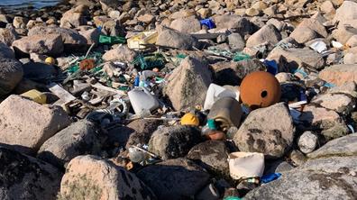 Amounts of litter among rocks on the coast.
