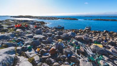 Marine litter on a rocky beach with a group of people having a break.