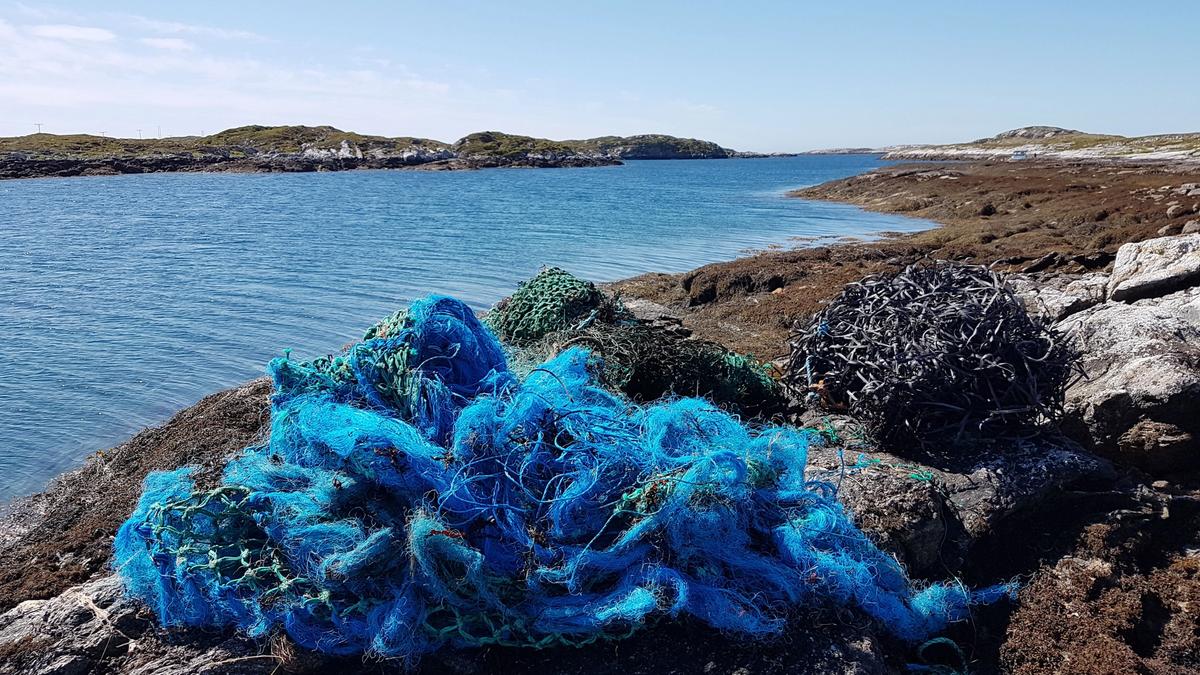 Blue fishing net laying on the rocks by the sea