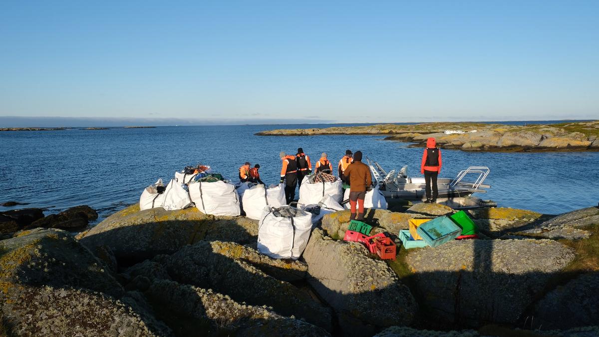 Beach cleaners on rocky cliffs with many big bags of marine litter.