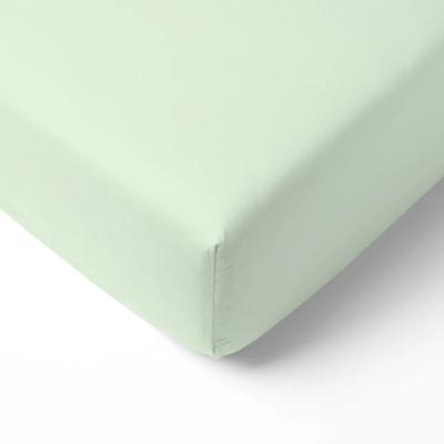 Sage green fitted crib sheet on a crib mattress