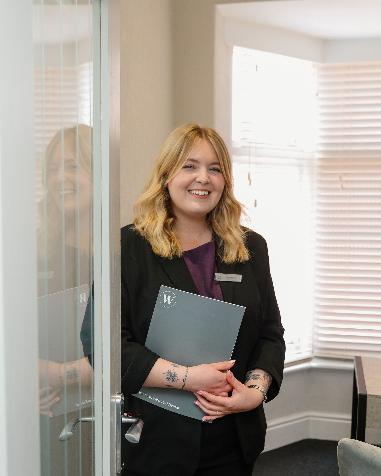 Receptionist in a West End Dental practice holding a Welcome to West End Dental folder
