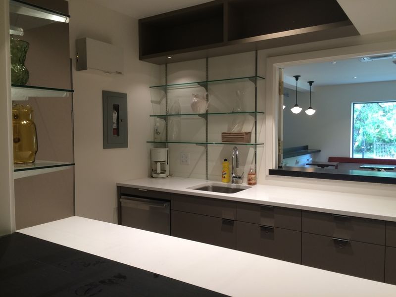 The servery, with glass shelves, a sink and a dishwasher under the counter