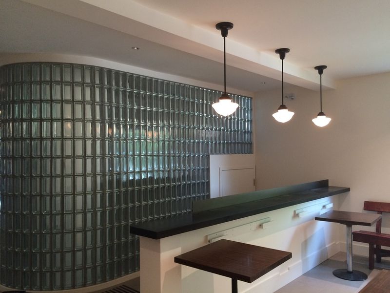 The lobby bar counter beside a glass-block wall, with stools and tables
