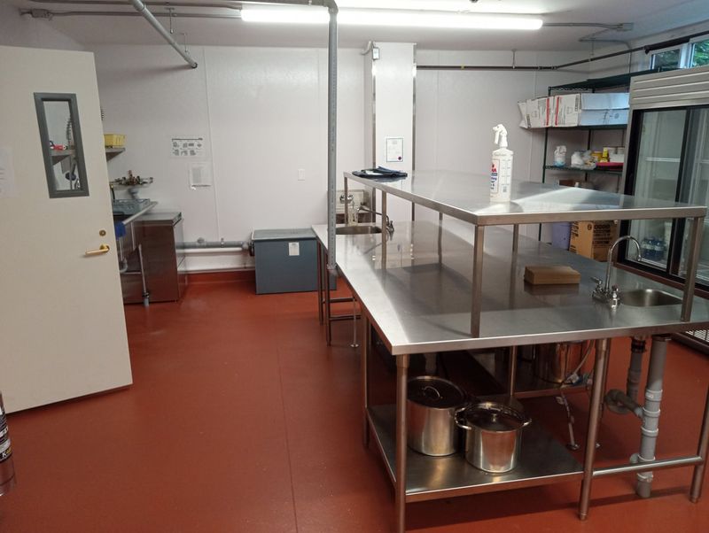 The kitchen prep tables and refrigerator on the red floor