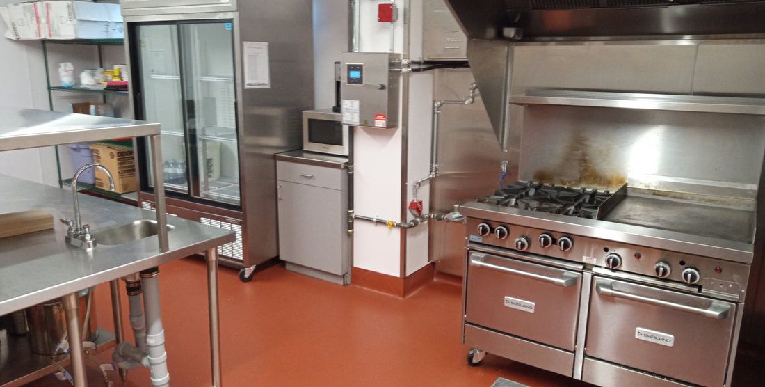 The commercial kitchen, with stainless prep tables and a gas range