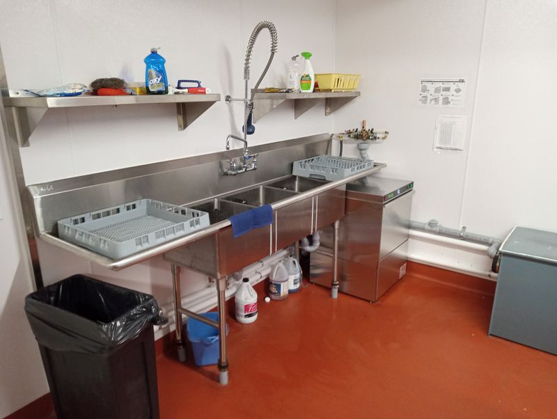 The kitchen's three dishwashing sinks and the commercial dishwasher