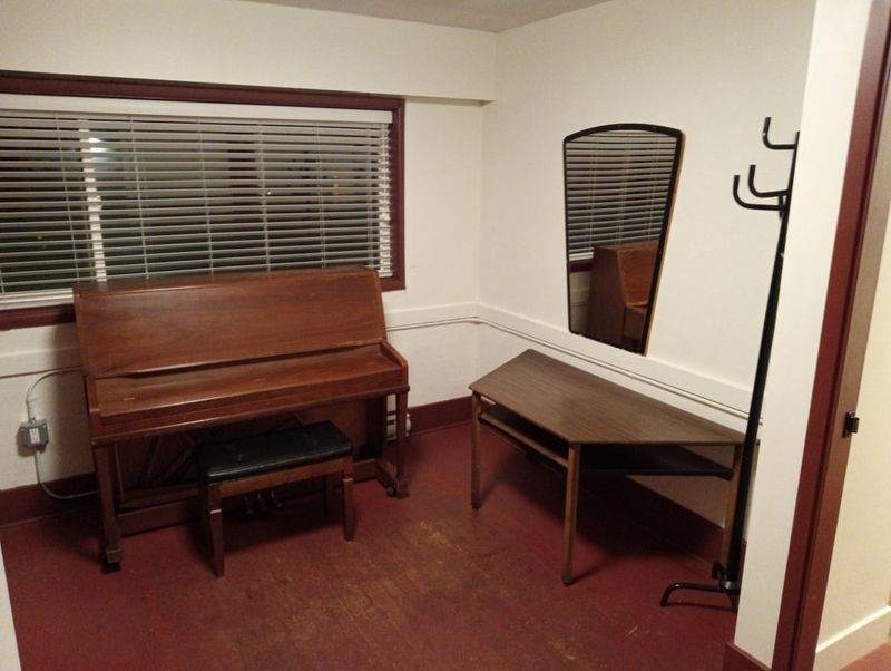 A dressing room with an upright piano and a bench under the window