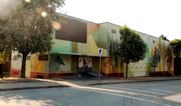 The length of the Hall's mural, seen from the sidewalk under the street trees