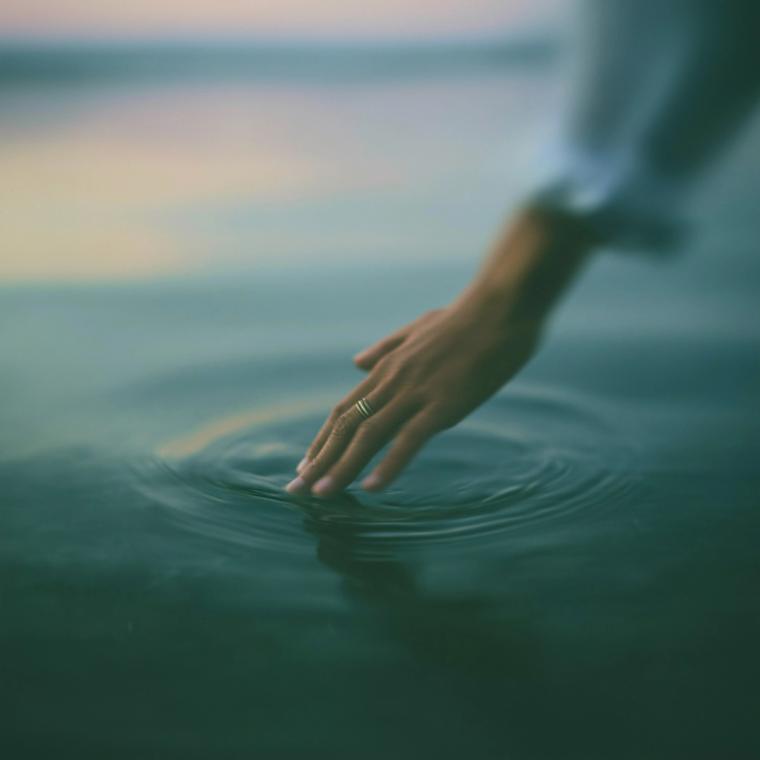 Eine Hand berührt die Wasseroberfläche