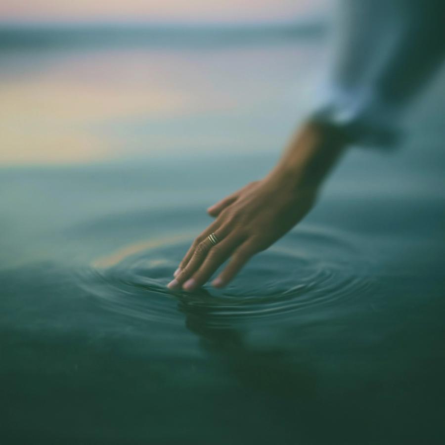 Eine Hand berührt die Wasseroberfläche