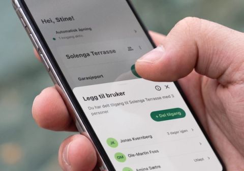 Nærbilde av en hånd som holder en telefon med Parqio-appen åpen på «Legg til bruker» – tilgangen til Solenga Terrasse er delt med tre personer.
