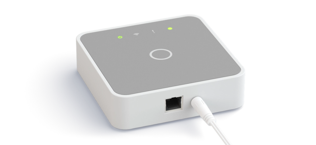 The Parqio base station seen from above at an angle, with indicator lights on top and network and power cables at the back