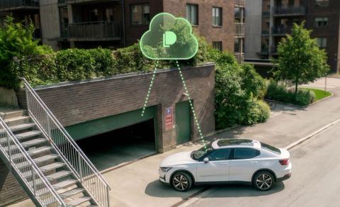 A white electric SUV approaches an underground residential parking garage entrance, with a green Parqio cloud-connectivity graphic overlaid above the access point.