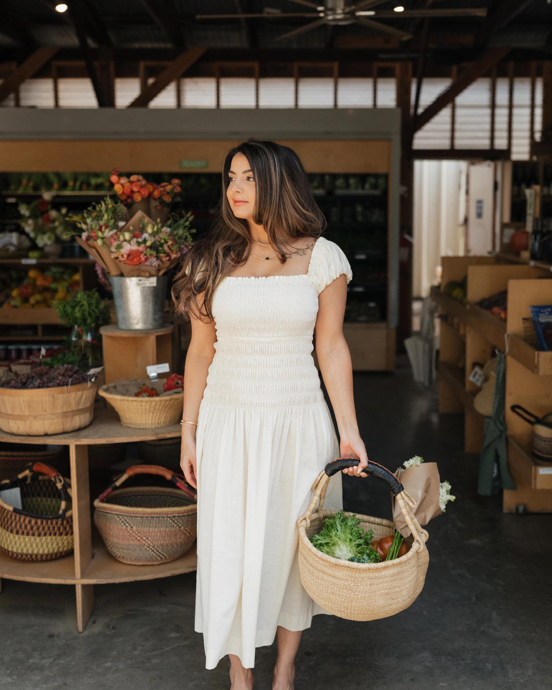 Saba holding a basket of fresh greens at a market
