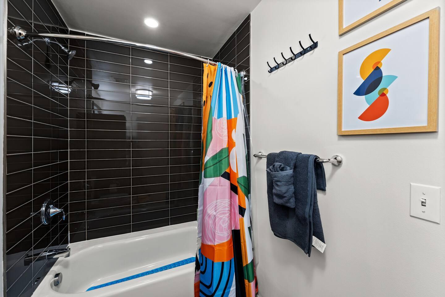 Bathroom with bathtub, toilet , vanity , big mirror, fresh towels , consumables include shampoo, conditioner, body wash, hair dryer.