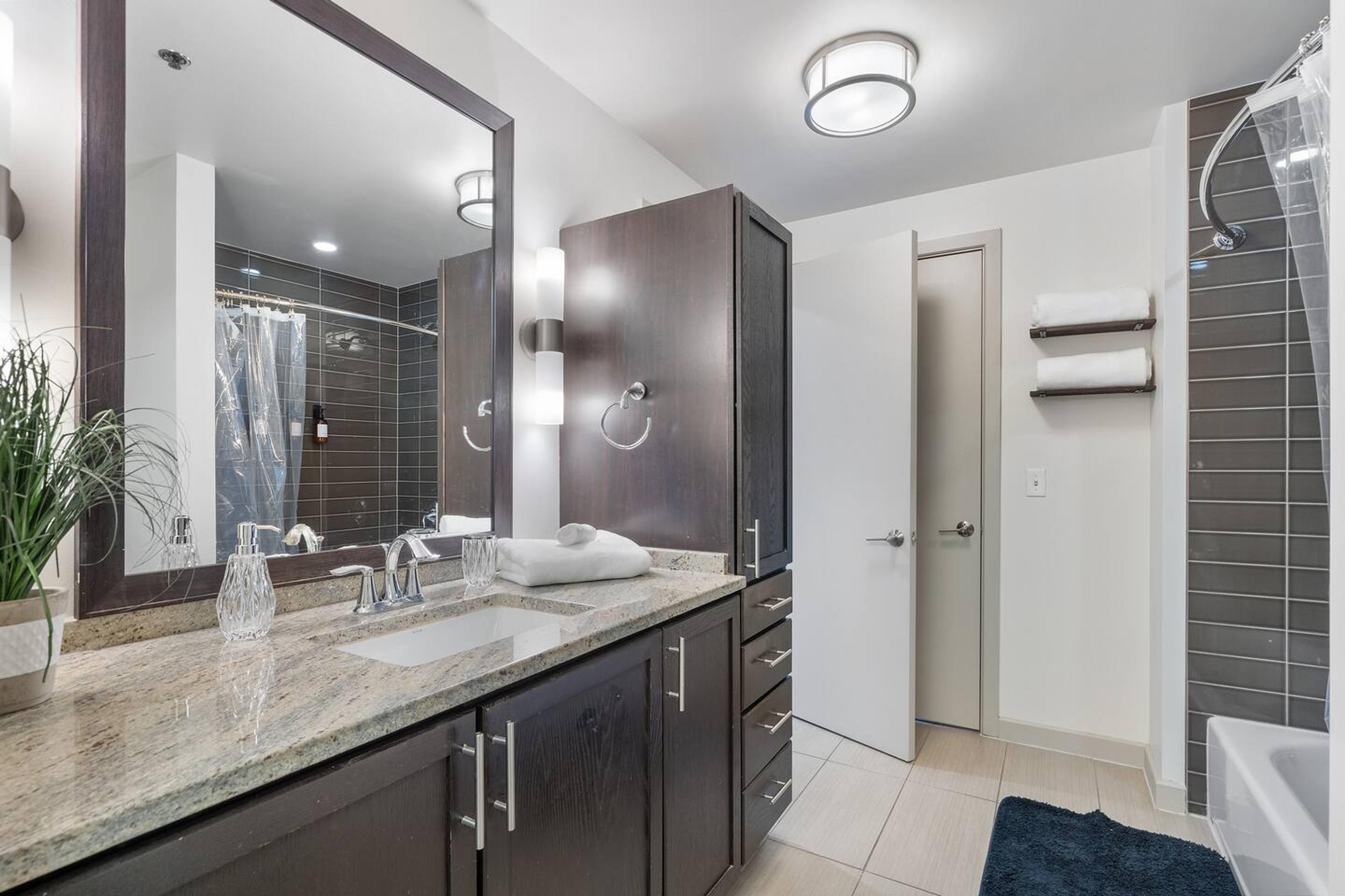 Bathroom with bathtub, toilet , vanity , big mirror, fresh towels , consumables include shampoo, conditioner, body wash, hair dryer.