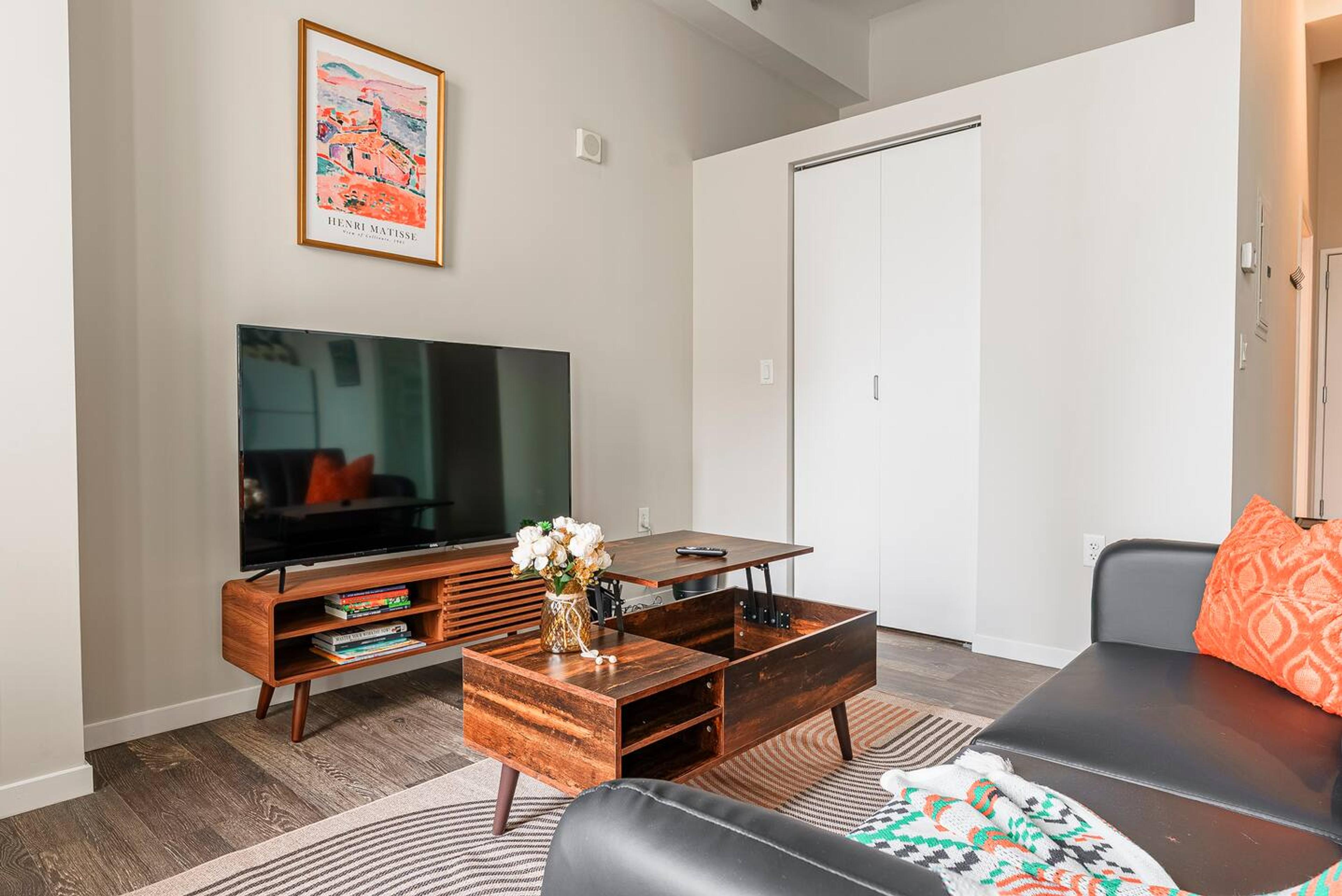 Living area accused with TV 65 inch smart, centre table and comfy couch.