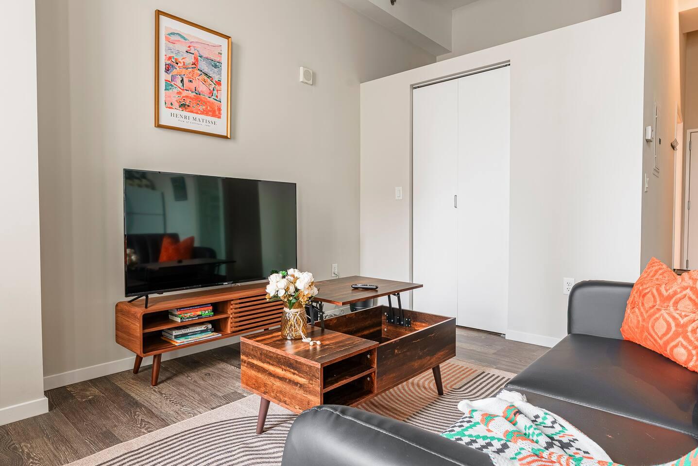 Living area accused with TV 65 inch smart, centre table and comfy couch.