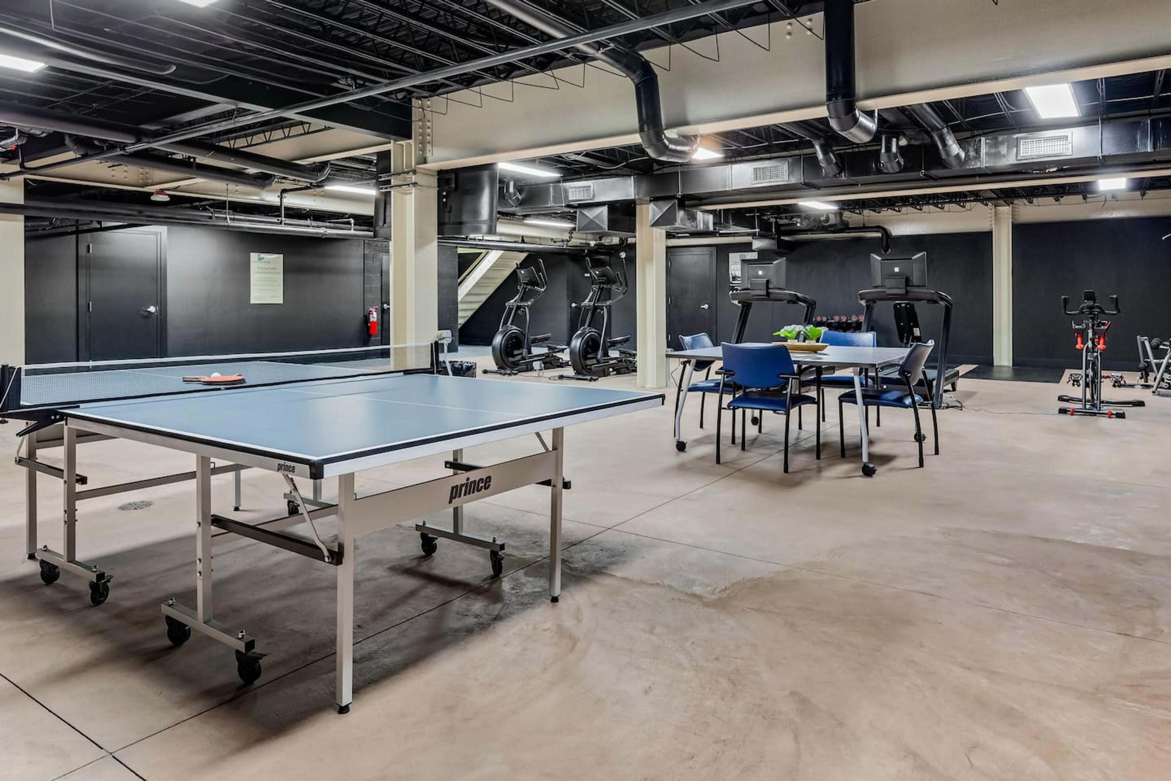 Common area with basic gym equipment and a game space for table tennis.