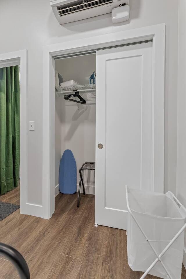 Bedroom 1 with a closet space providing hangers for clothes and an ironing machine with iron board