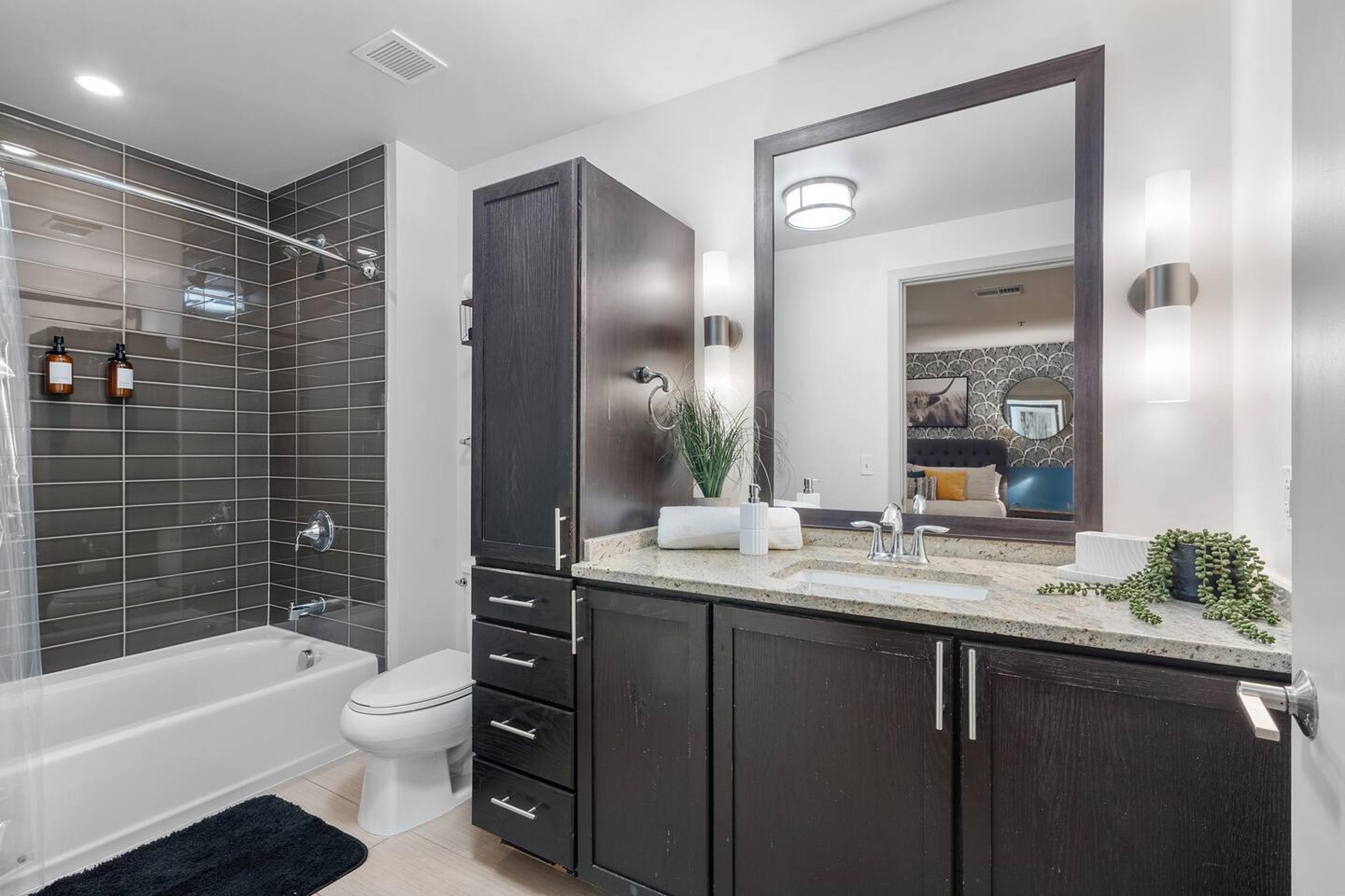Bathroom with bathtub, toilet , vanity , big mirror, fresh towels , consumables include shampoo, conditioner, body wash, hair dryer.
