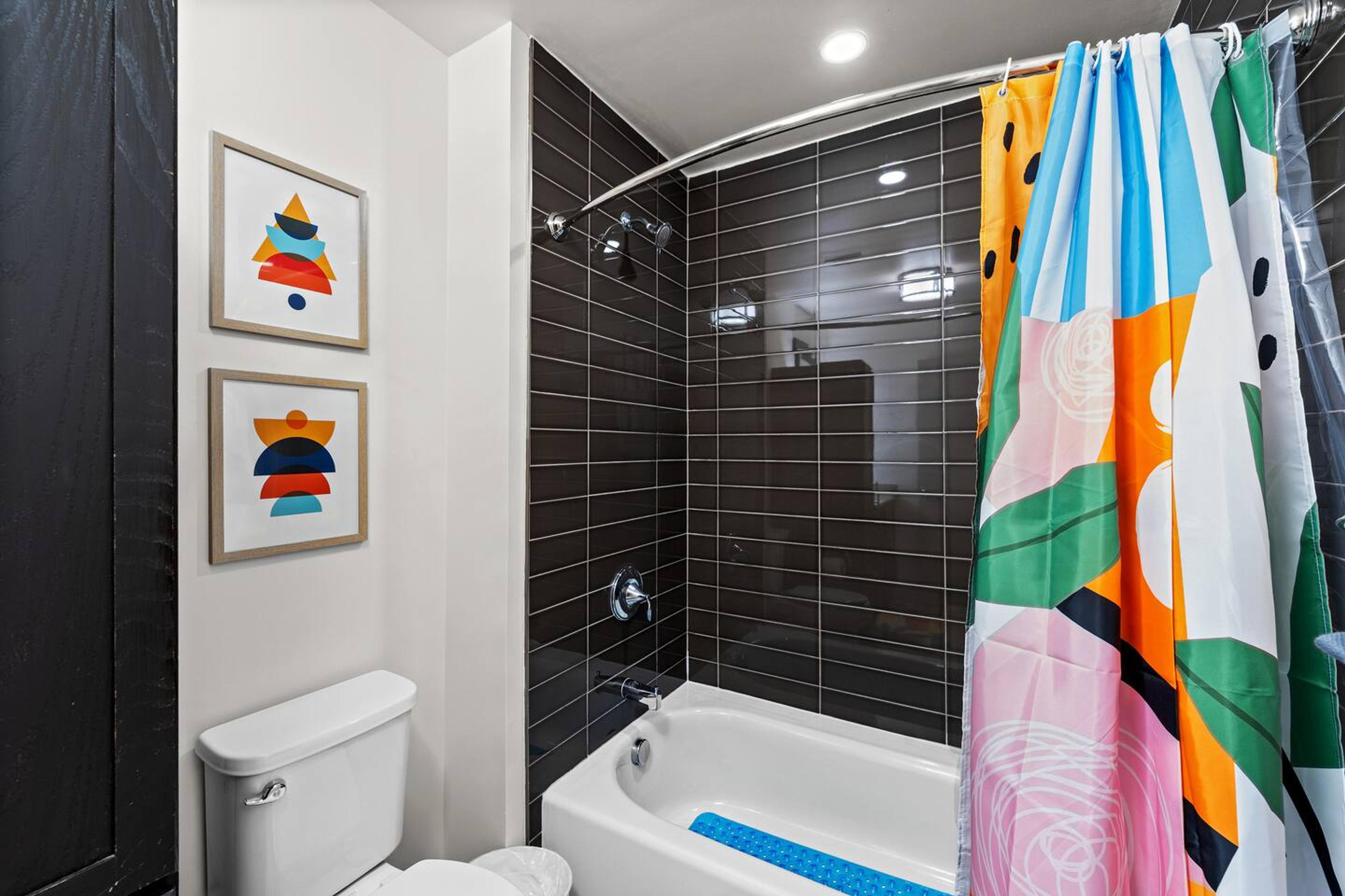 Bathroom with bathtub, toilet , vanity , big mirror, fresh towels , consumables include shampoo, conditioner, body wash, hair dryer.