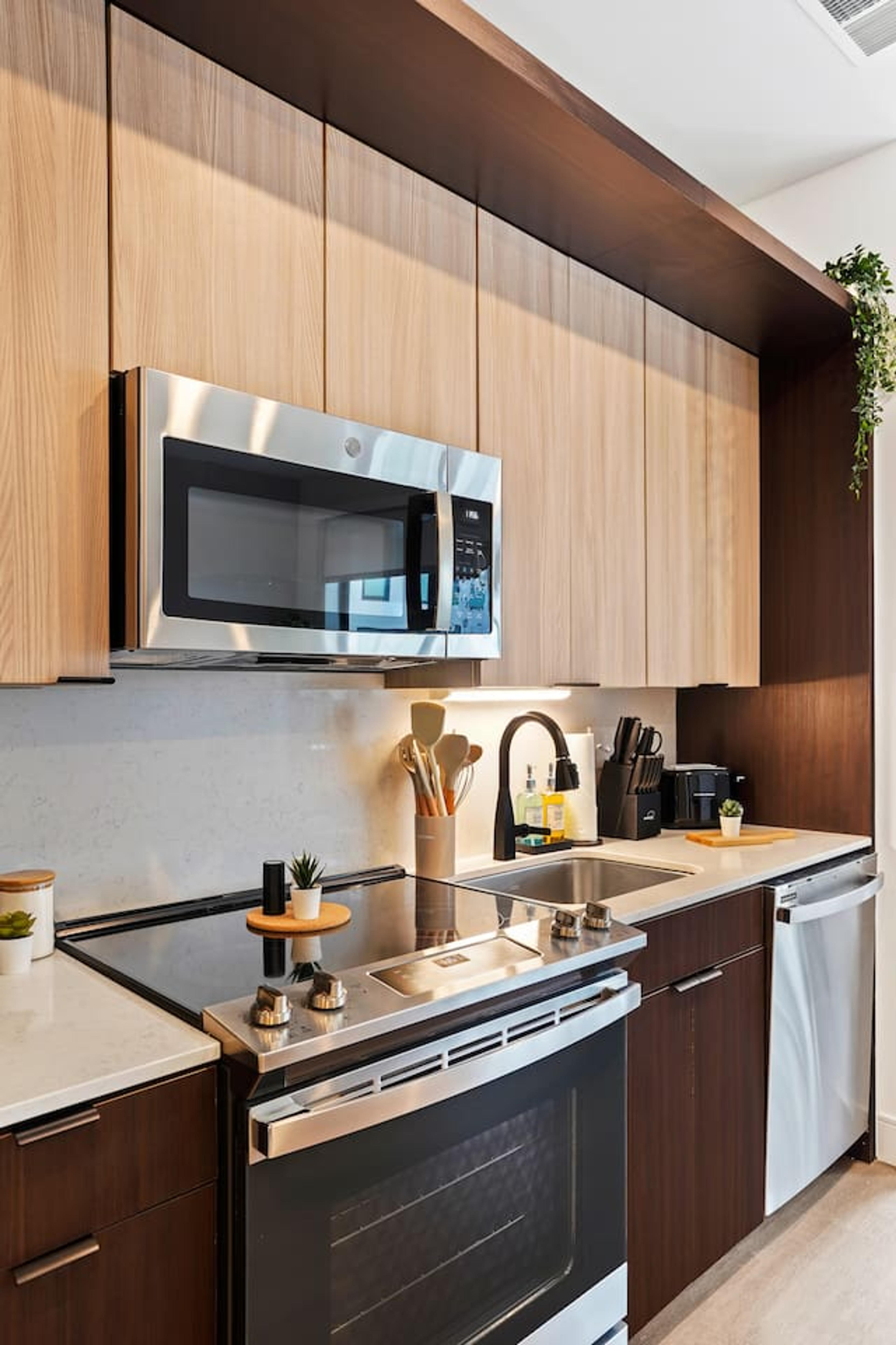 Closer image of kitchen equipped with stainless steel stove, micro-wave oven, cooking spoons, knife set, toaster and many more