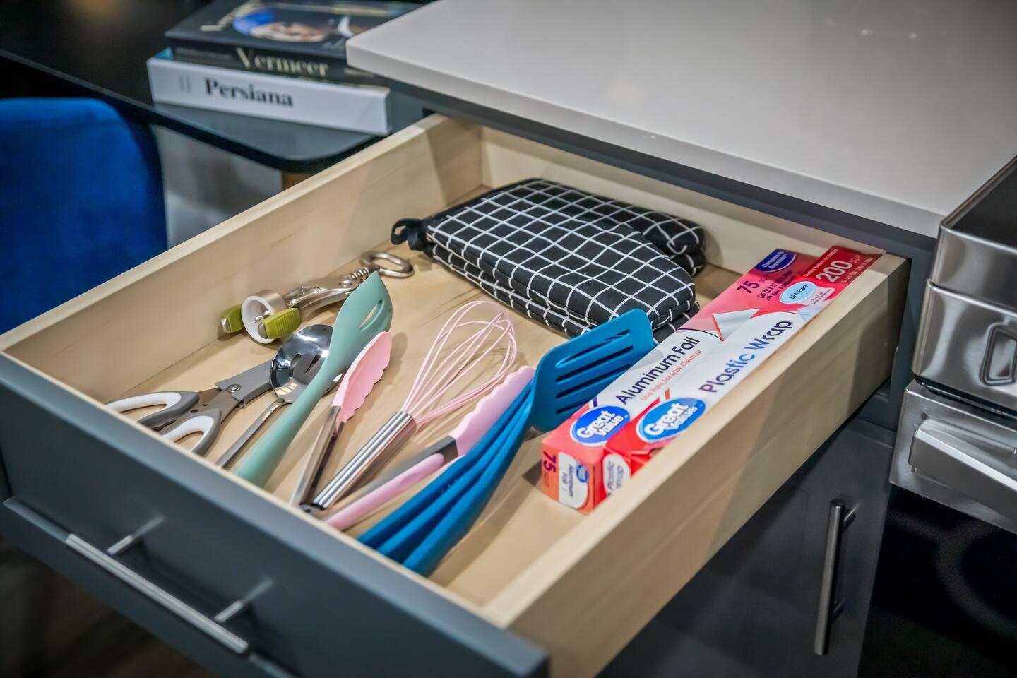 Kitchen area with spatulas, whiskers, scissors ,oven mitts, mini torch, aluminum wraps and also plastic wraps.