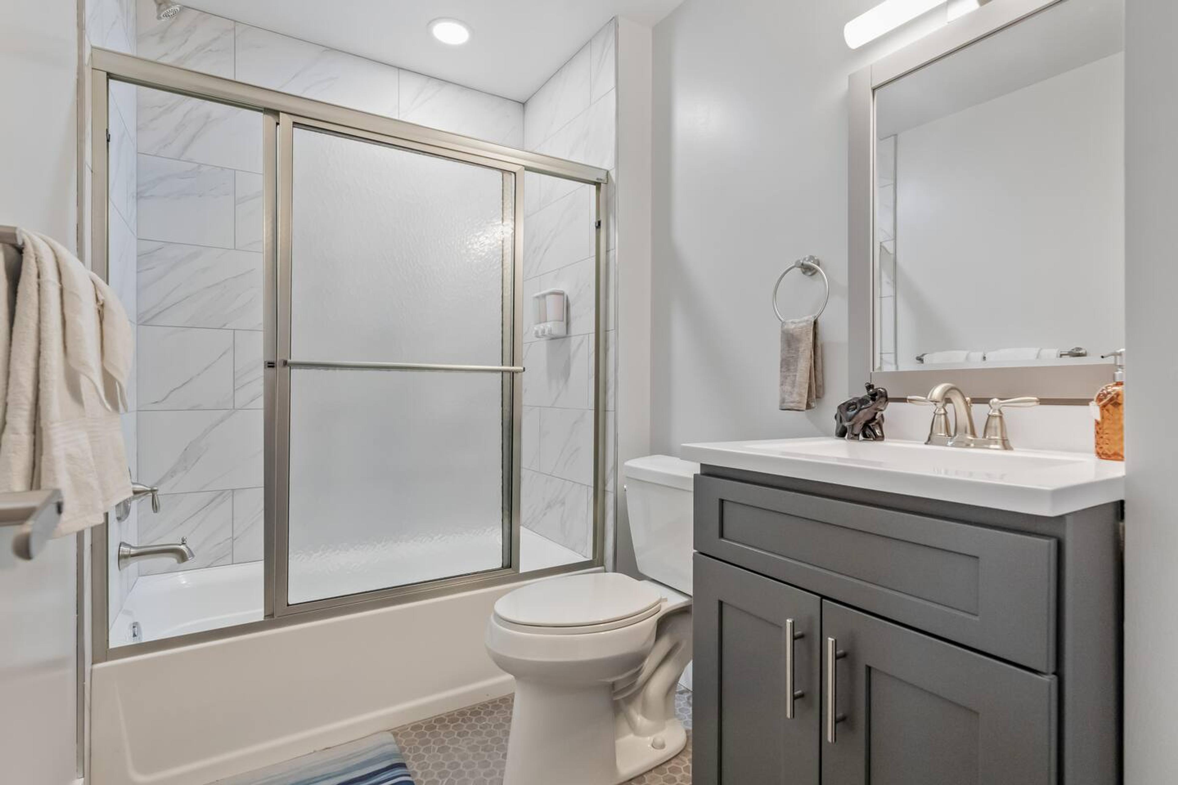 Bathroom space with bathtub, clean towels, soap and a hair dryer.