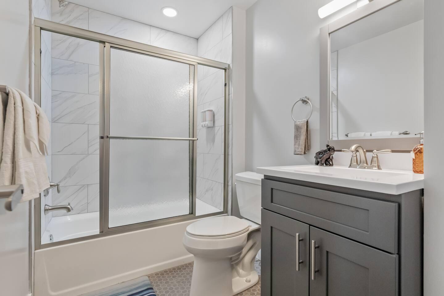 Bathroom space with bathtub, clean towels, soap and a hair dryer.