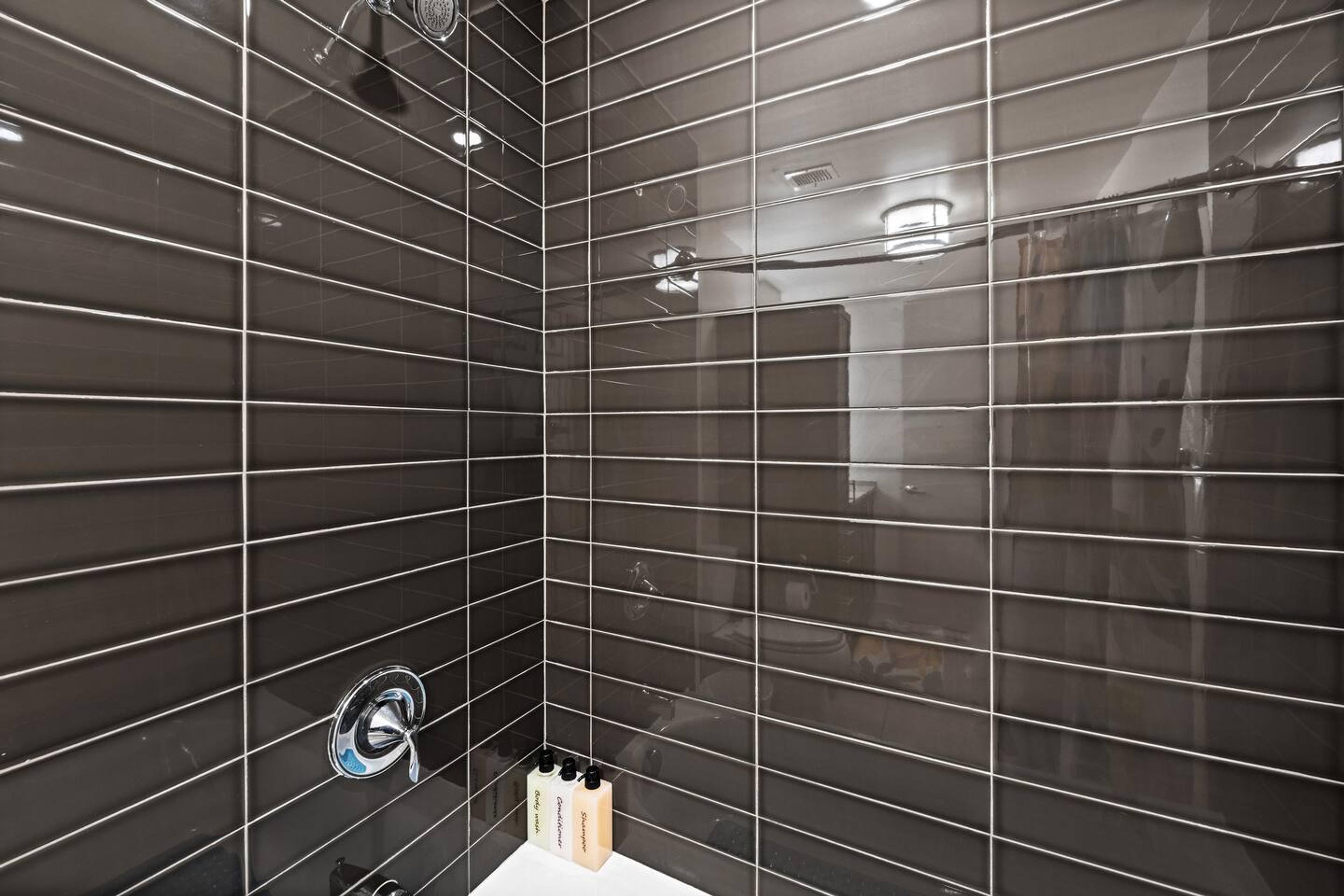Bathroom with bathtub, toilet , vanity , big mirror, fresh towels , consumables include shampoo, conditioner, body wash, hair dryer.