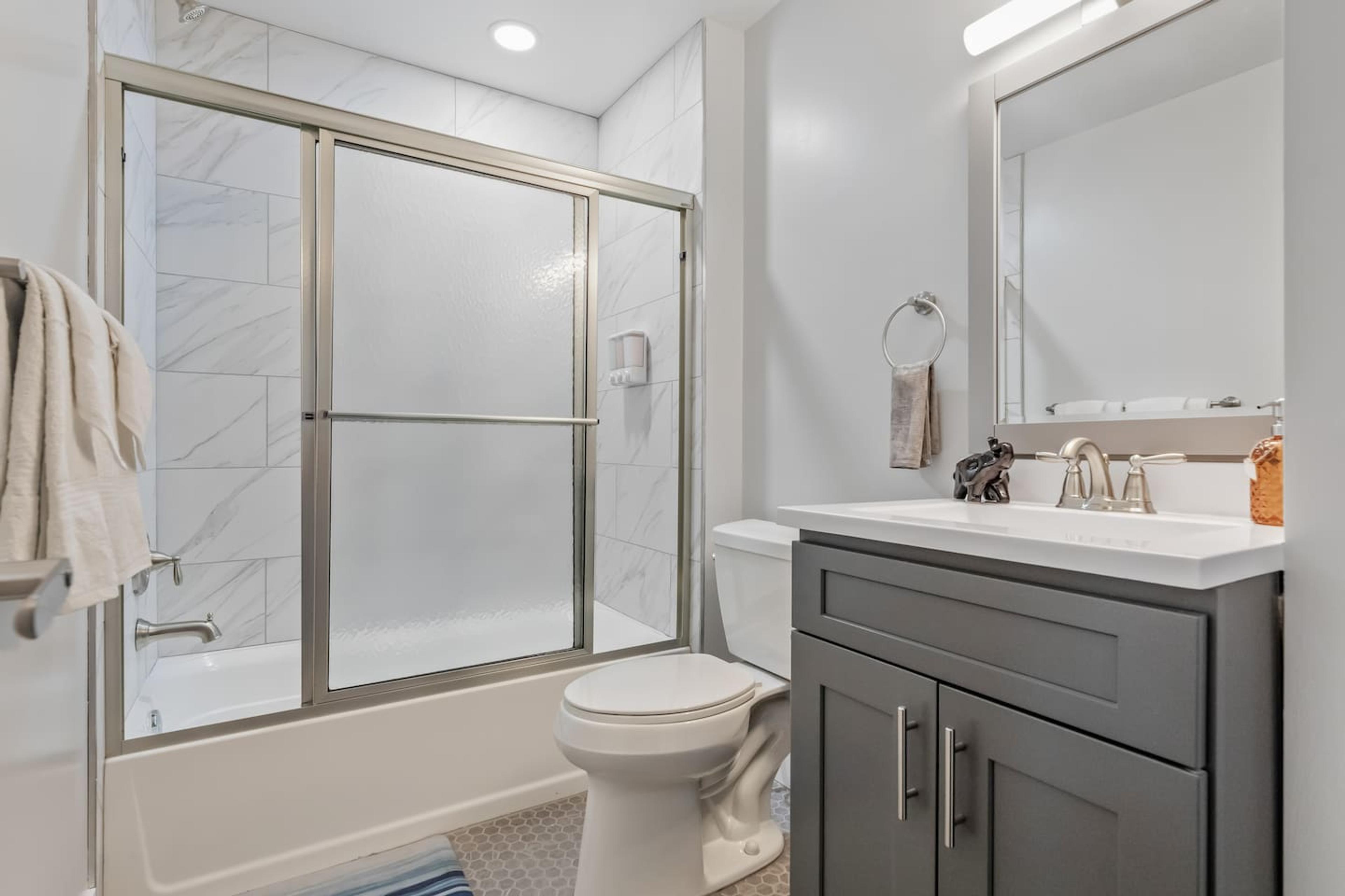 Bathroom space with bathtub, clean towels, soap and a hair dryer.