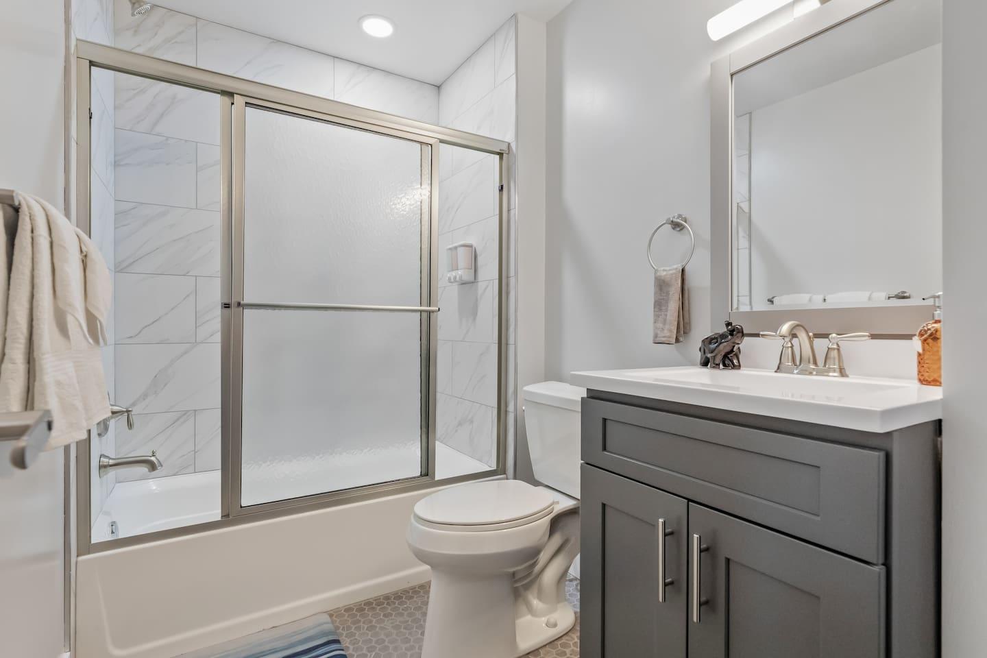 Bathroom space with bathtub, clean towels, soap and a hair dryer.