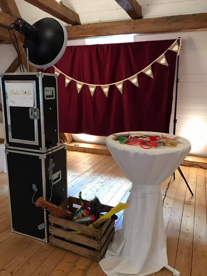 Fotobox Boxxee mit rotem Vorhang und bereitgelegten Requisiten