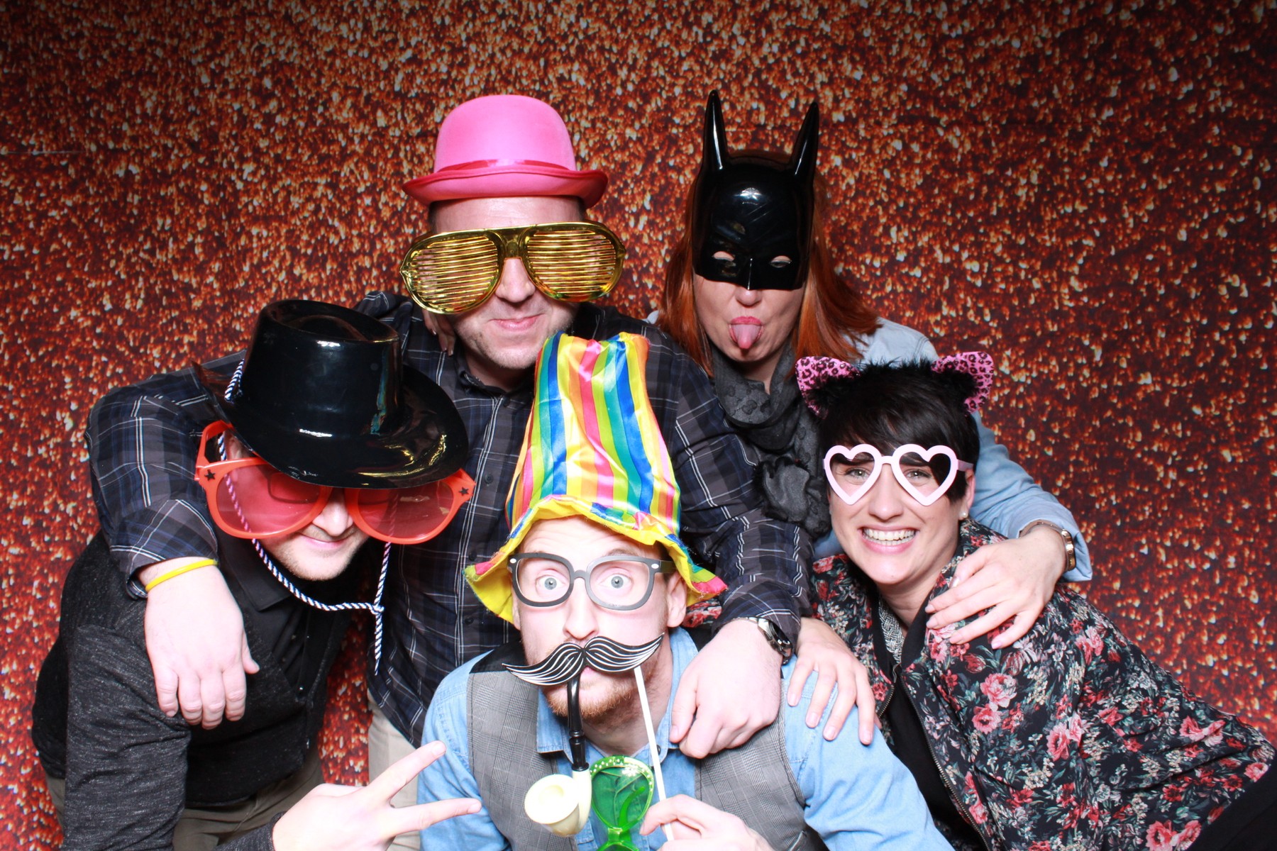 Verkleidete Gäste lachen gemeinsam vor dem glitzernden Fotobox-Hintergrund