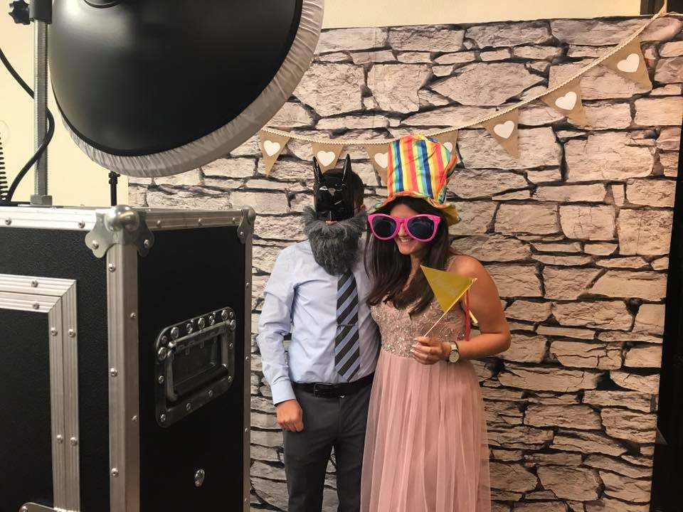 Paar mit bunten Brillen vor einer Steinwand an der Fotobox