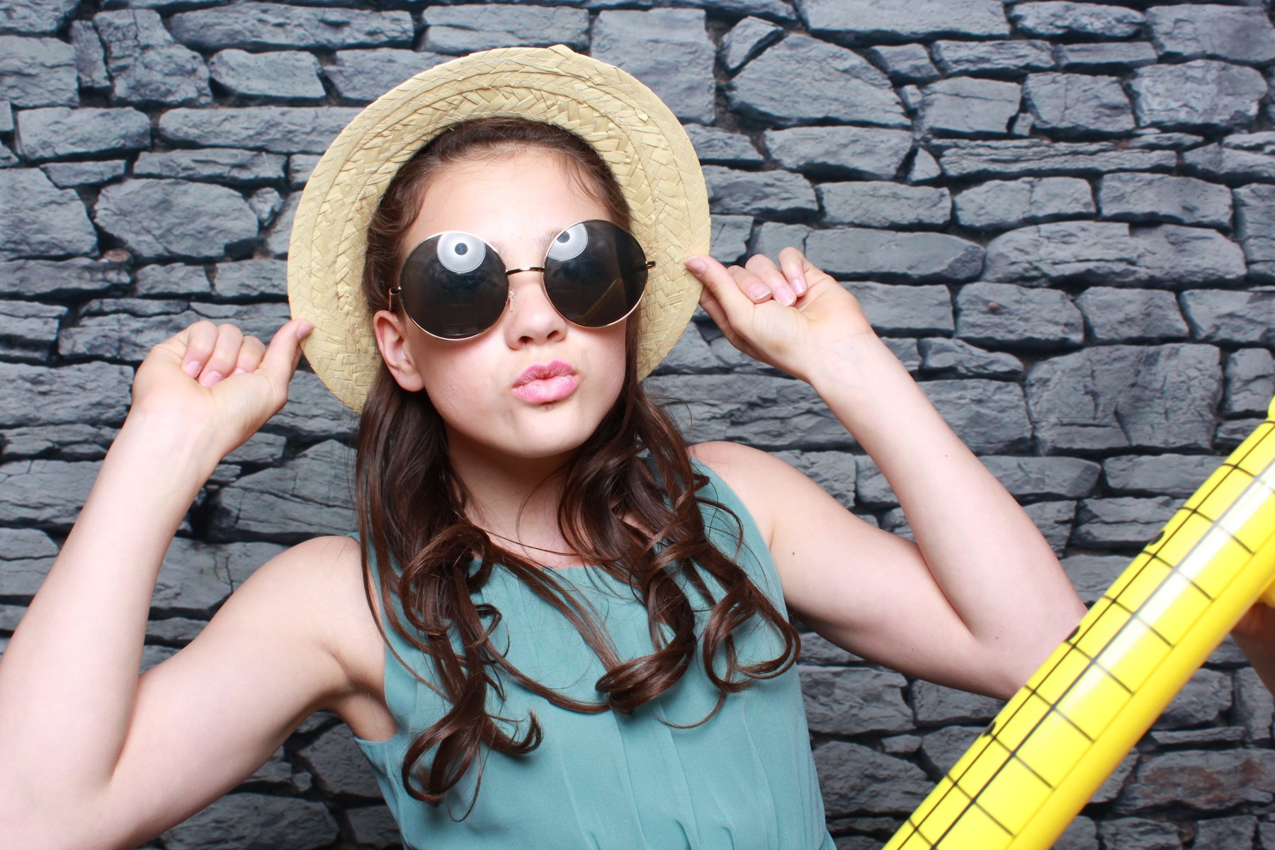 Gast mit Hut, Sonnenbrille und Luftgitarre vor der Fotobox