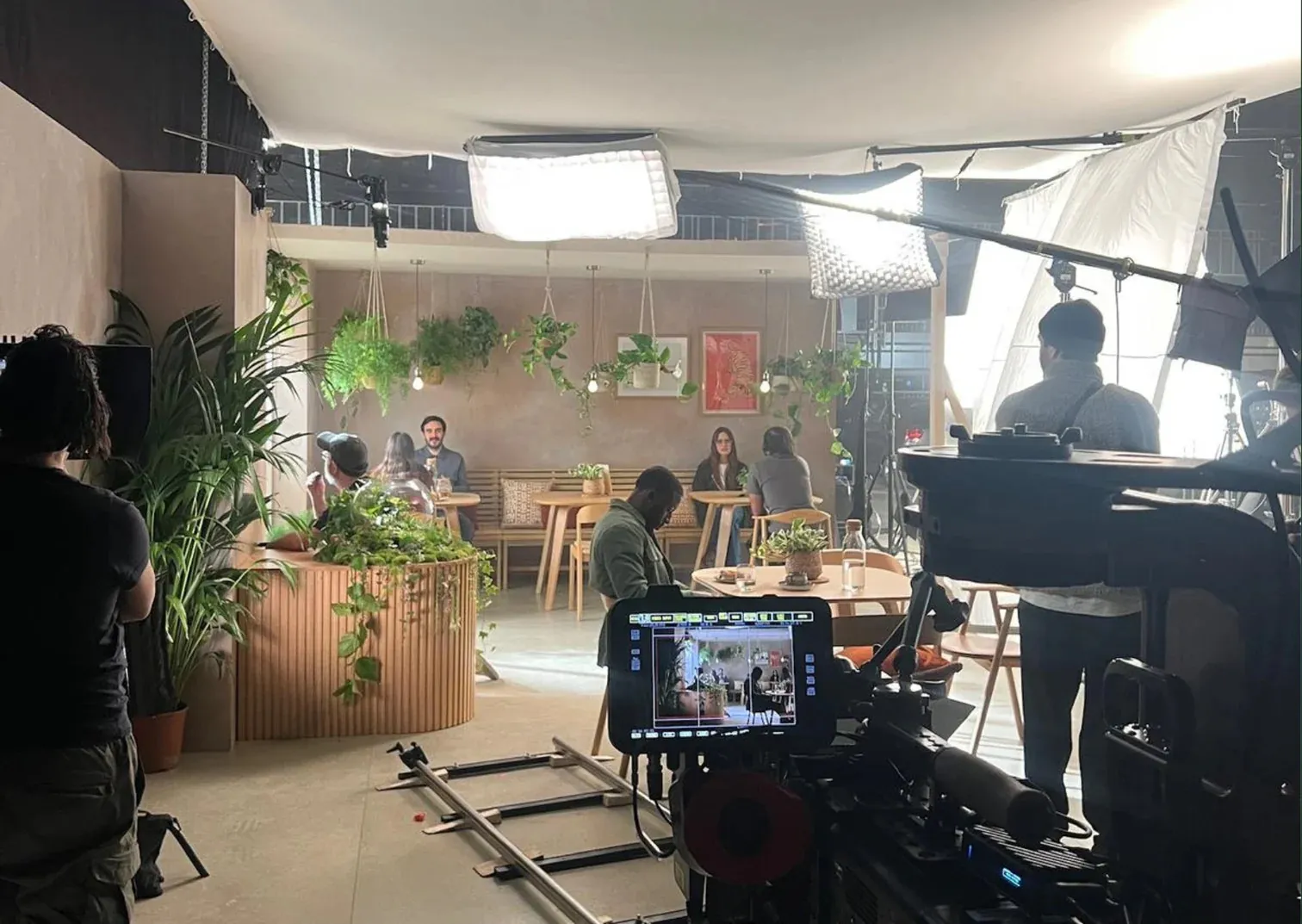 Behind the scenes on the Samsung film set: camera and crew facing a café scene with the terrarium on a fluted counter