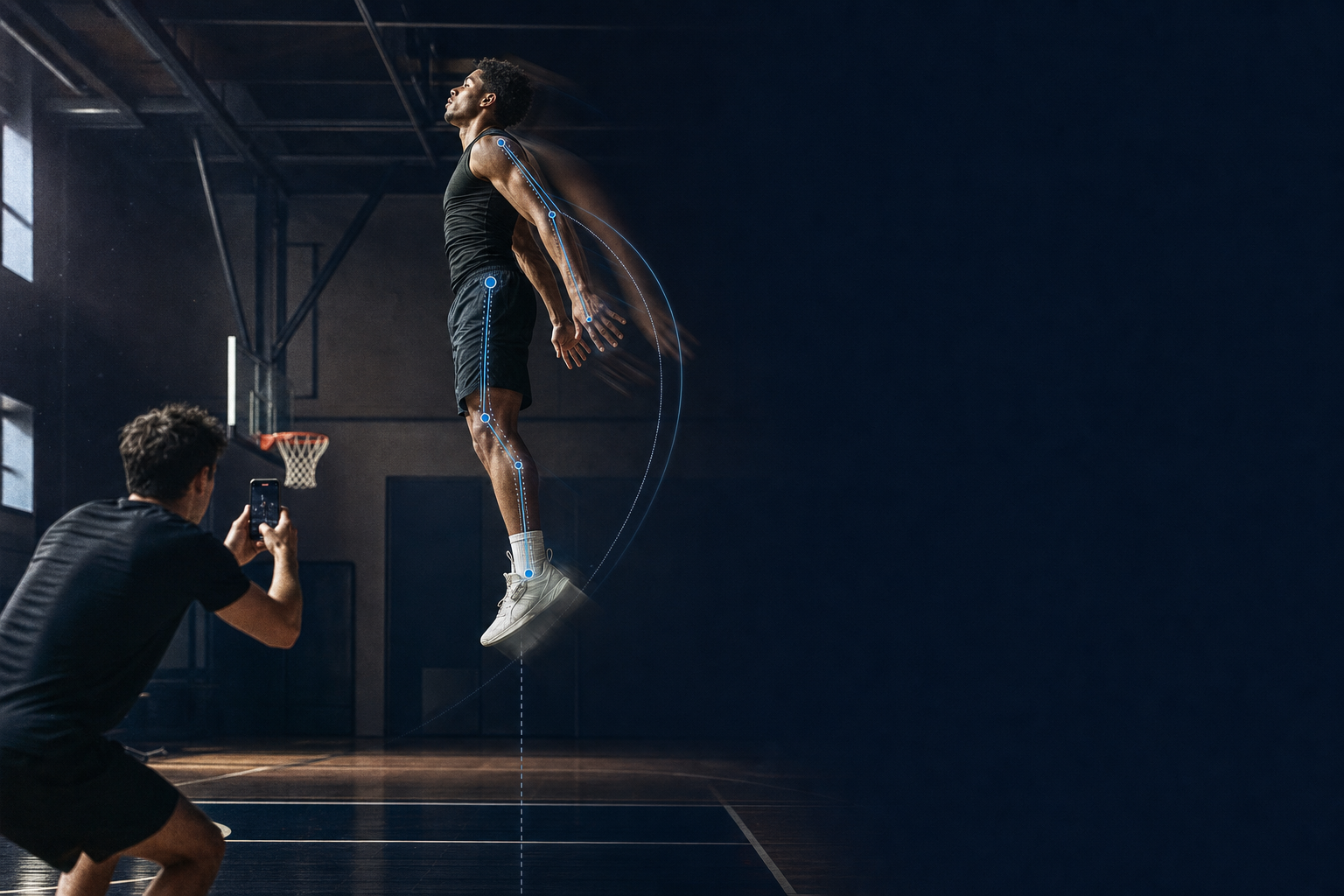 A basketball player at the peak of a countermovement jump in an empty gym while a teammate films the takeoff from the side on a phone