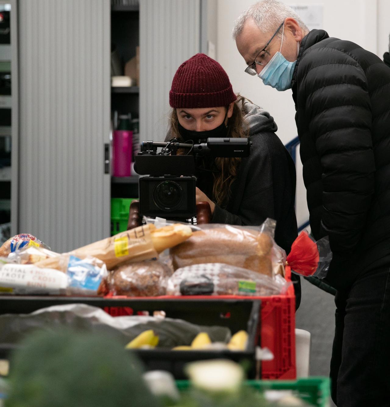 the camera operator and director wearing face masks filming in the food bank
