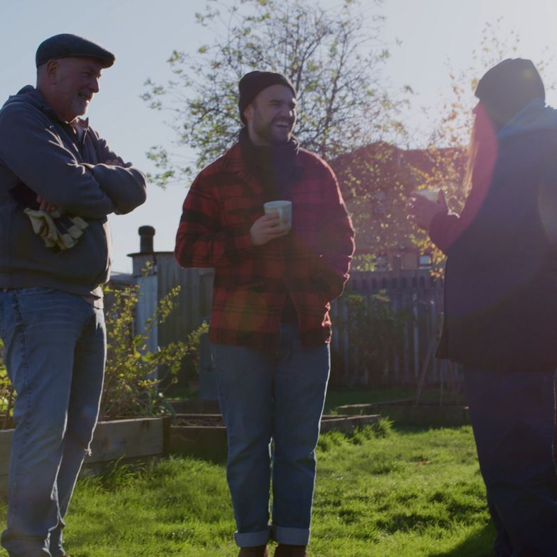 Three charity workers chatting in a community garden Three charity workers chatting in a community garden