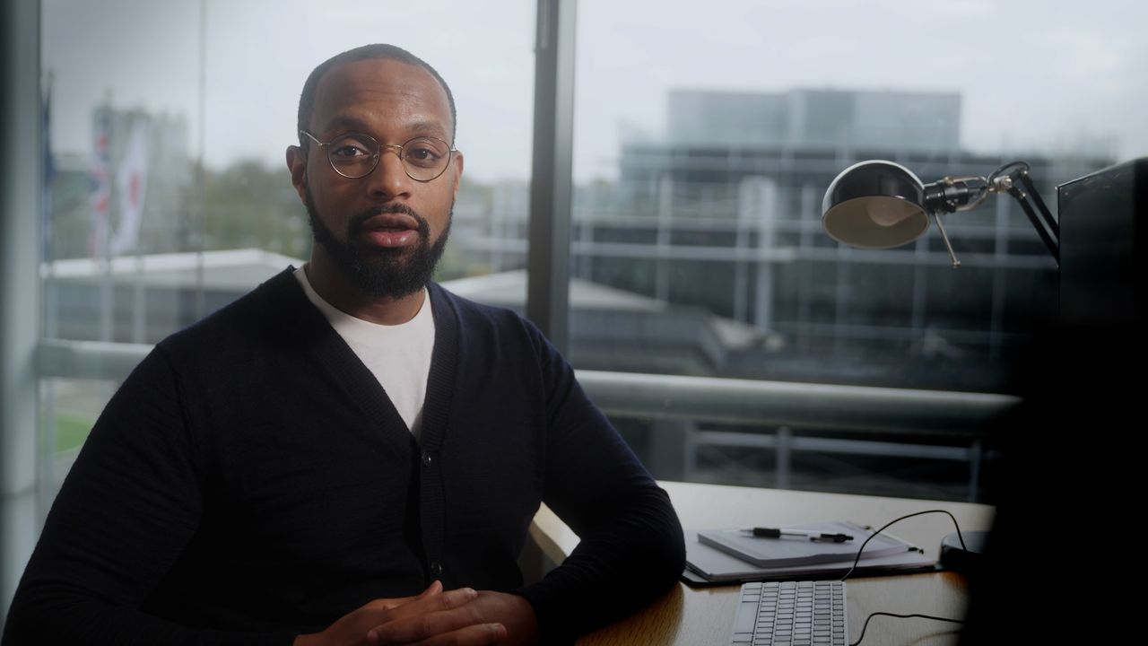 Man with glasses delivering piece to camera